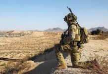 A US soldier in camo surveils a desert valley in New Mexico