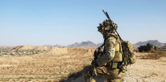 A US soldier in camo surveils a desert valley in New Mexico