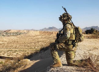 A US soldier in camo surveils a desert valley in New Mexico