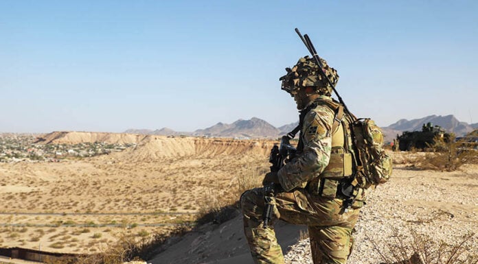 A US soldier in camo surveils a desert valley in New Mexico