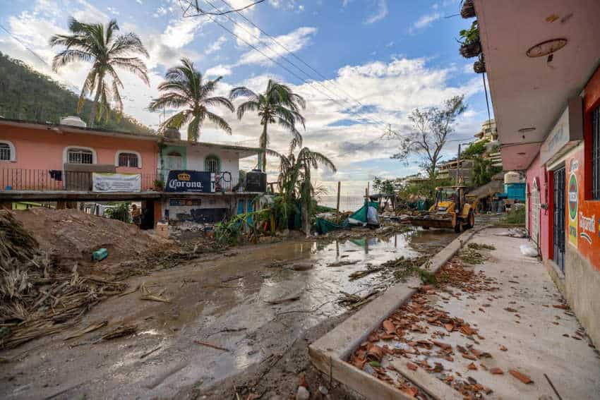 A backhoe clears mud and debris from around homes and businesses in downtown Puerto Vallarta, Mexico, after Tropical Storm Lidia.