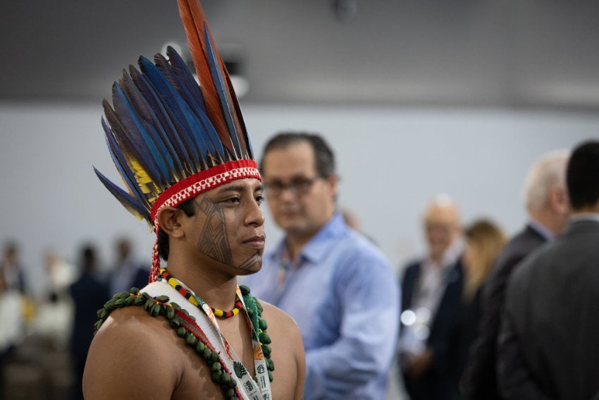An Indigenous activist from the Amazon, in traditional headdress, at the COP30 climate summit, representing the communities that often feel the most impact from global climate change.
