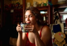 A woman closes her eyes, enjoying the aroma of a traditional Mexican warm drink in a beautiful blue and white Talavera-style ceramic mug.