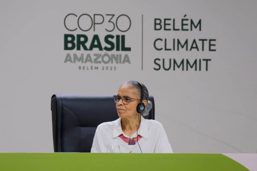 Brazil's environment minister Marina Silva seated at a table during a meeting at the COP30 Belém Climate Summit, wearing a headset for translation.