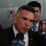 Mexico News Daily, Mexican politician speaking to press with PRI logo in background.
