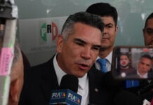 Mexico News Daily, Mexican politician speaking to press with PRI logo in background.