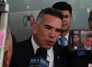 Mexico News Daily, Mexican politician speaking to press with PRI logo in background.