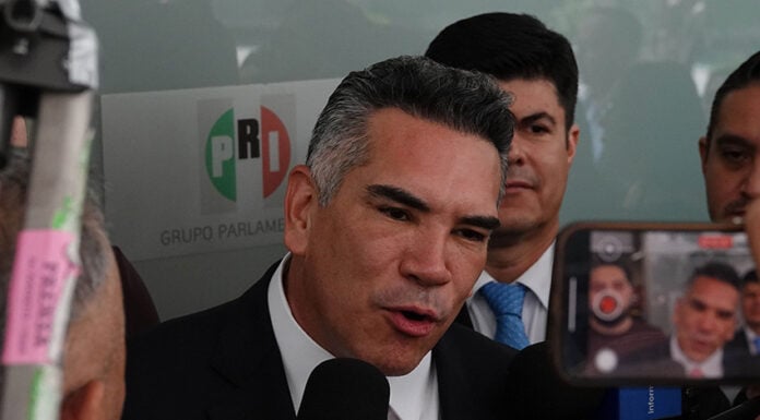 Mexico News Daily, Mexican politician speaking to press with PRI logo in background.
