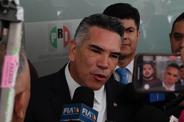 Mexico News Daily, Mexican politician speaking to press with PRI logo in background.