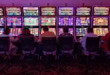 Sillouetted people sit at glowing neon slot machines