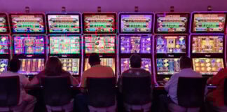 Sillouetted people sit at glowing neon slot machines