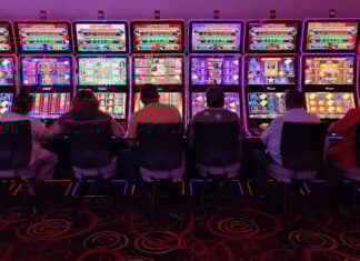 Sillouetted people sit at glowing neon slot machines