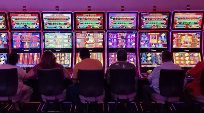 Sillouetted people sit at glowing neon slot machines