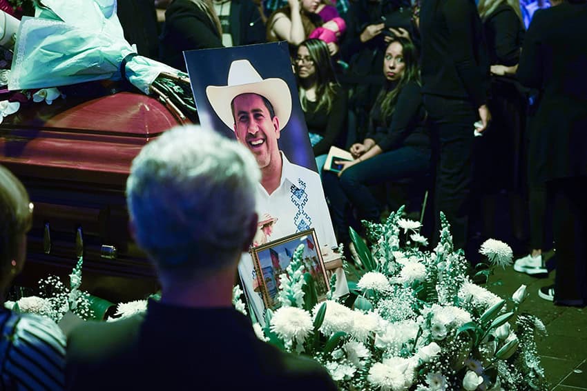 A photo of former Uruapan Mayor Carlos Manzo on a coffin with flowers surrounded by people dressed in black