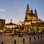 People walk by a Guadalajara cathedral lit up in the evening