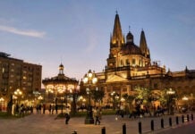 People walk by a Guadalajara cathedral lit up in the evening