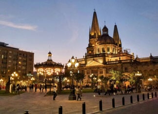 People walk by a Guadalajara cathedral lit up in the evening