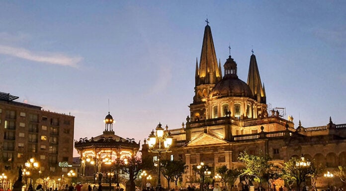People walk by a Guadalajara cathedral lit up in the evening