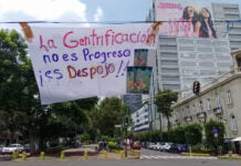 A banner reading "La Gentrificación no es progreso, es despojo" hangs over a Mexico City street