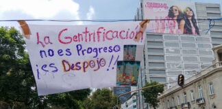 A banner reading "La Gentrificación no es progreso, es despojo" hangs over a Mexico City street