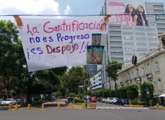 A banner reading "La Gentrificación no es progreso, es despojo" hangs over a Mexico City street