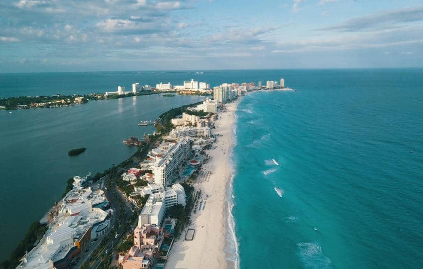 Aerial view of the Cancun Hotel Zone and turquoise Caribbean coastline, highlighting the Restricted Zone where foreigners must use a bank trust when buying land in Mexico to build a home or acquiring beachfront property.