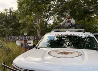 A National Guard truck drives past a sign reading Rancho Sac Lol