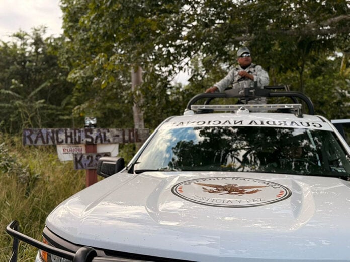 A National Guard truck drives past a sign reading Rancho Sac Lol