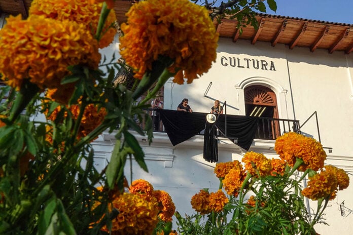 A government building adorned with a giant black bow and wide-brimmed hat, with marigolds in the foreground