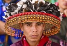 Close-up portrait of a Wixárika man wearing a traditional hat adorned with feathers and intricate beadwork