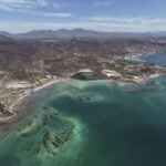 Aerial view of Mexico's rugged coastline with clear turquoise waters and arid mountain terrain in the background
