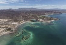 Aerial view of Mexico's rugged coastline with clear turquoise waters and arid mountain terrain in the background