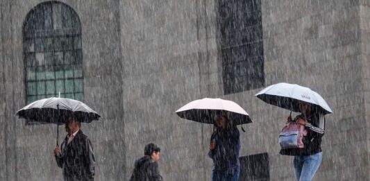 four people walking in the rain with umbrellas