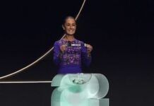 Sheinbaum holds up a small ribbon with the word Mexico at the World Cup draw on Dec. 5