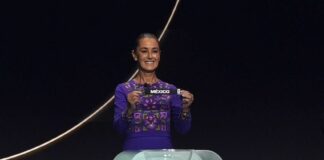 Sheinbaum holds up a small ribbon with the word Mexico at the World Cup draw on Dec. 5