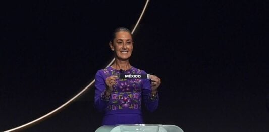 Sheinbaum holds up a small ribbon with the word Mexico at the World Cup draw on Dec. 5