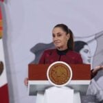 President Sheinbaum smiles and gestures from the podium of her morning press conference