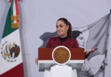 President Sheinbaum smiles and gestures from the podium of her morning press conference