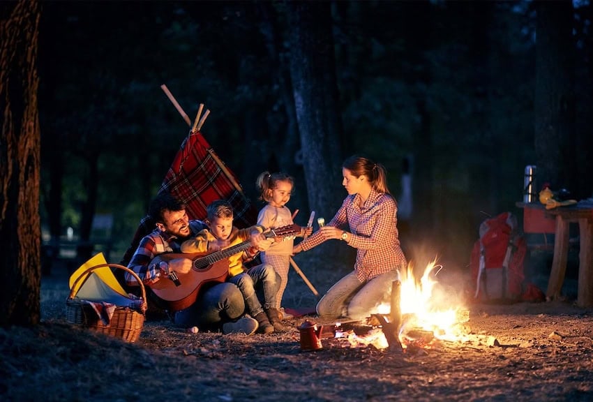 A family playing guitar and singing around a campfire