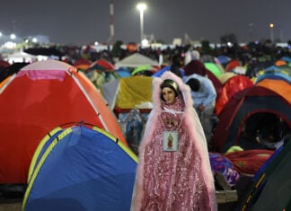 A Virgin of Guadalupe figure in sparkling pink robes watches over a plaza filled with colorful camping tents