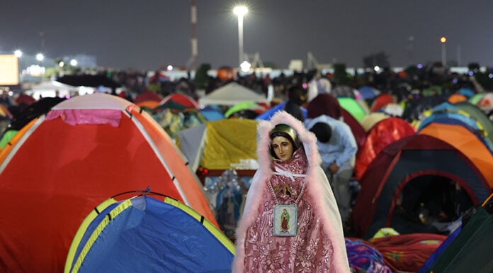 A Virgin of Guadalupe figure in sparkling pink robes watches over a plaza filled with colorful camping tents