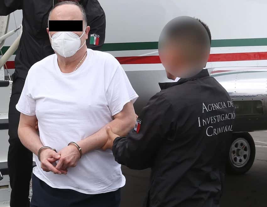 César Duarte disembarking from an aircraft in handcuffs
