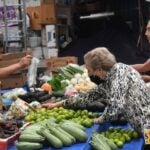 An old woman buying vegetables at a market stall