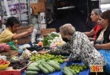 An old woman buying vegetables at a market stall