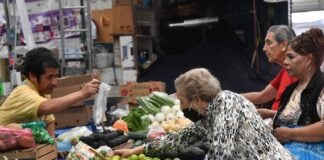 An old woman buying vegetables at a market stall