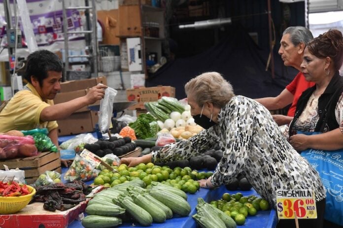 An old woman buying vegetables at a market stall