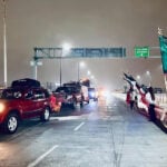Government agents wave Mexican flags as a caravan of cars drives down a highway at night