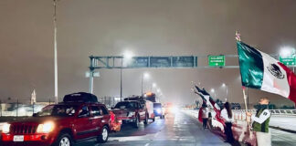 Government agents wave Mexican flags as a caravan of cars drives down a highway at night