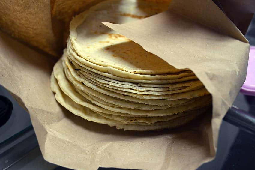 A pile of handmade tortillas reasting on brown paper packaging.