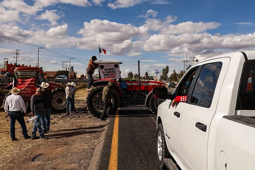Cars wait on a highway blocked by tractors bearing protest signs